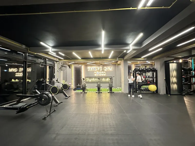 The Evolve Gym Cross area with rowers, air bikes and a turf strip under the lit sign