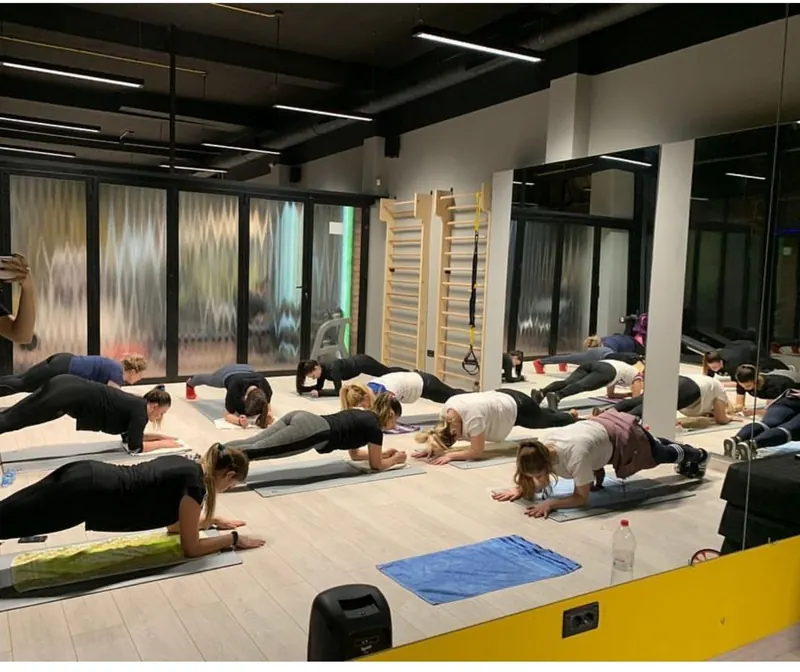A Pilates class holding a plank on mats in the studio