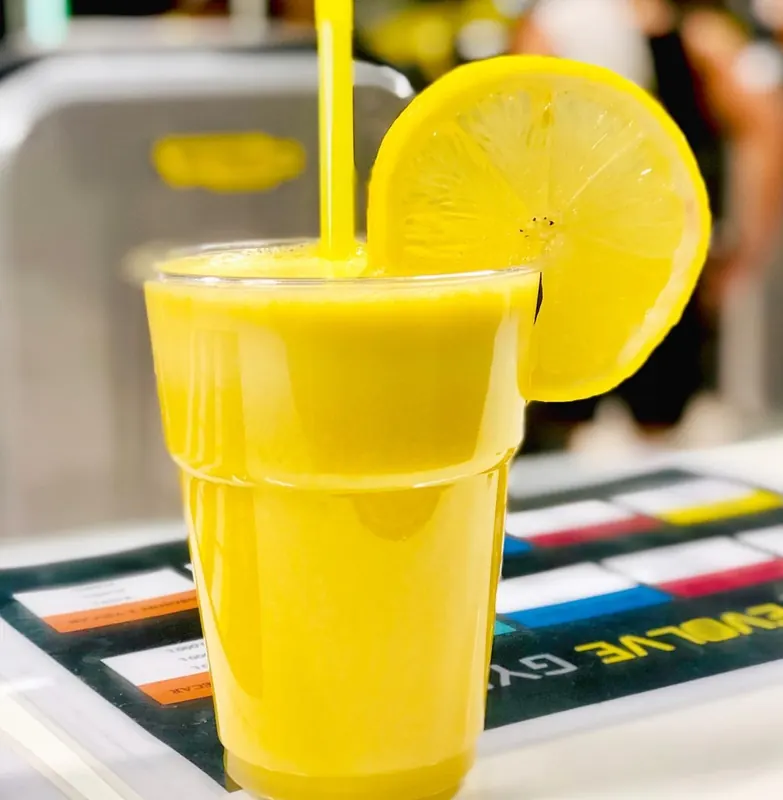 A fresh yellow smoothie with a lemon slice on the Evolve Gym counter