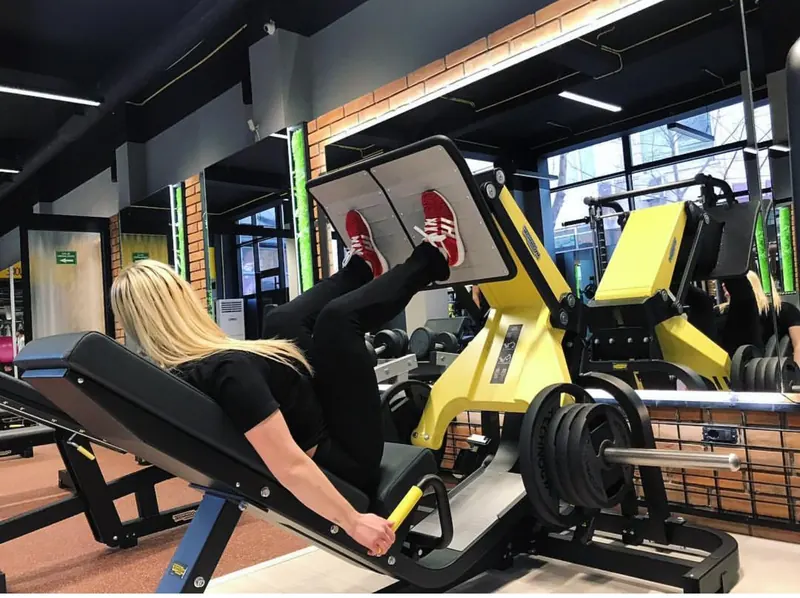 A member on a yellow Technogym leg press